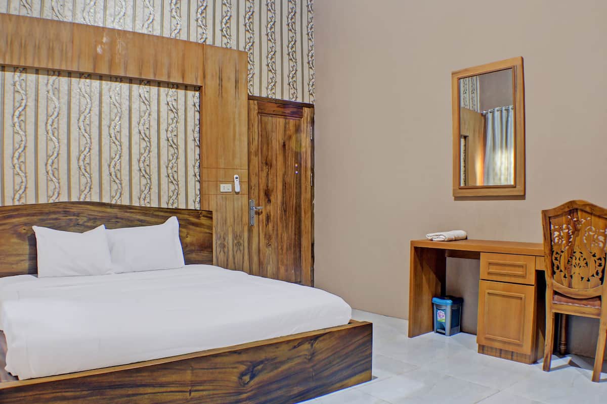A bedroom with a wooden bed, a desk, and a mirror.