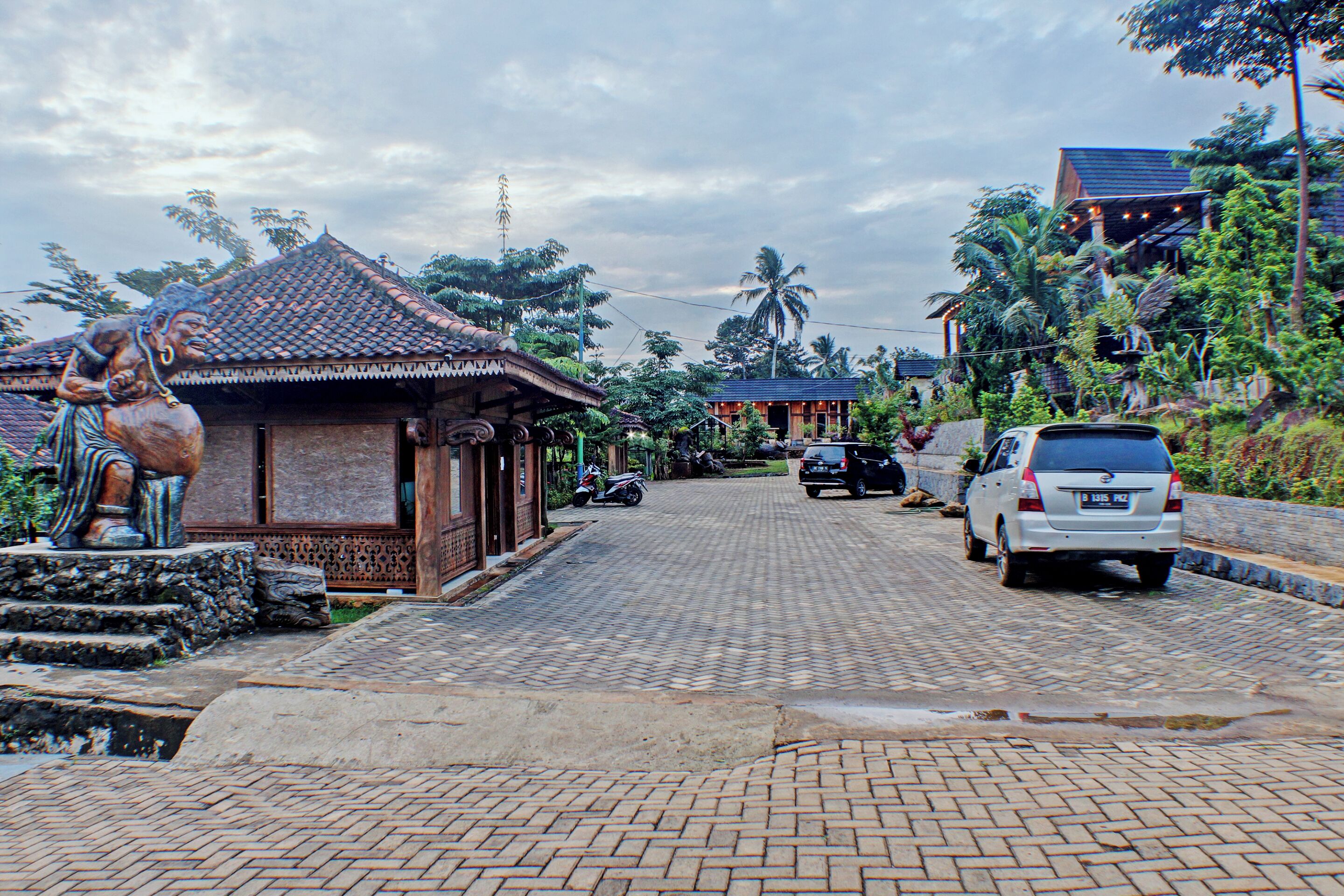 A paved street with a traditional building on the left and a modern car on the right.