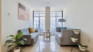 Una sala moderna con dos sofás, una mesita redonda y plantas en macetas.