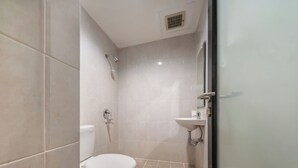 Un baño pequeño y moderno con inodoro, ducha y lavamanos.
