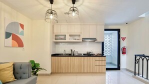 Una cocina moderna con armarios de madera clara, encimera negra e iluminación colgante.