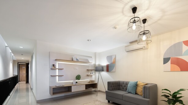 Una sala de estar moderna con un sofá gris, un televisor de pantalla plana, una mesa de centro y una planta en maceta.