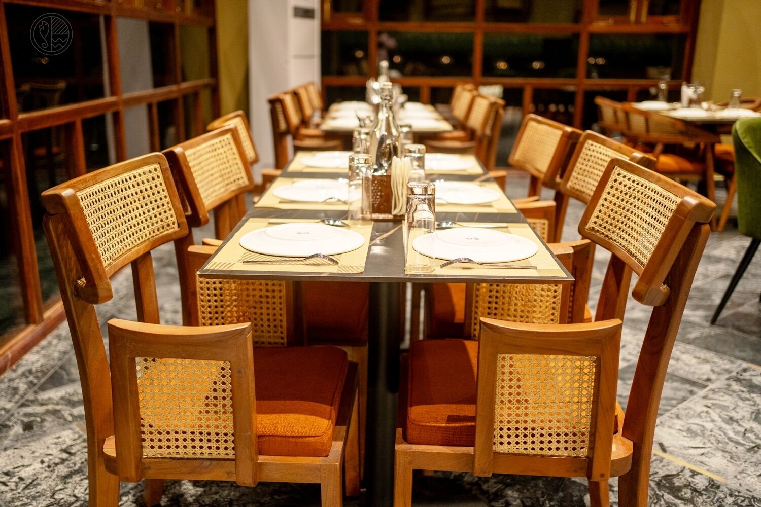 A restaurant with wooden chairs and tables, arranged in a long dining area.