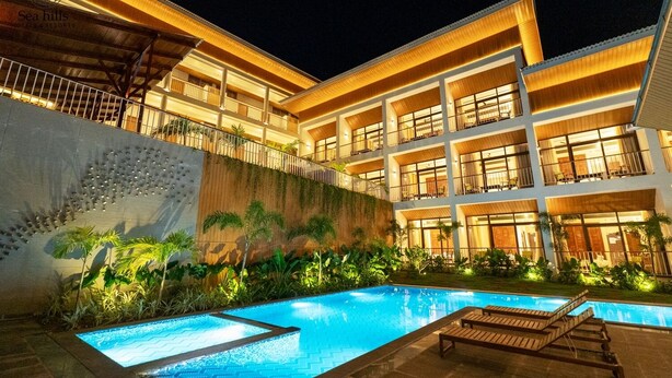 A hotel with a swimming pool, multiple balconies, and a well-lit facade. - Sea Hills Resort Havelock (Port Blair)