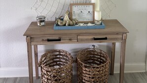 A wooden table with a sign reading "WELCOME TO THE BEACH," a framed menu, candles, and decorative items.