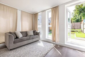 Relax in this serene living room with a sofa set by a large window overlooking a well-maintained backyard.