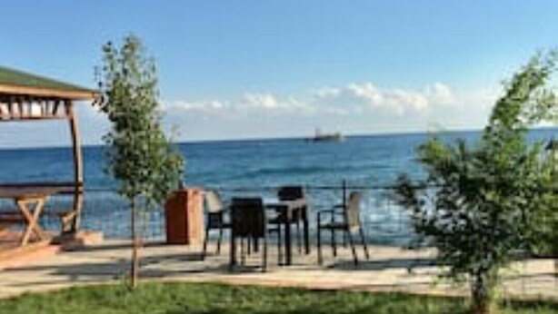 An outdoor seating area with a wooden pergola, tables, and chairs, overlooking a body of water. - Modern, Quiet & Comfy ~ King Beds ~ Free Parking! (LONDON)