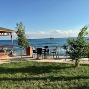 An outdoor seating area with a wooden pergola, tables, and chairs, overlooking a body of water. - Modern, Quiet & Comfy ~ King Beds ~ Free Parking! (LONDON)