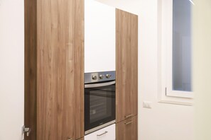 Una cocina con armarios de madera, horno integrado y ventana.