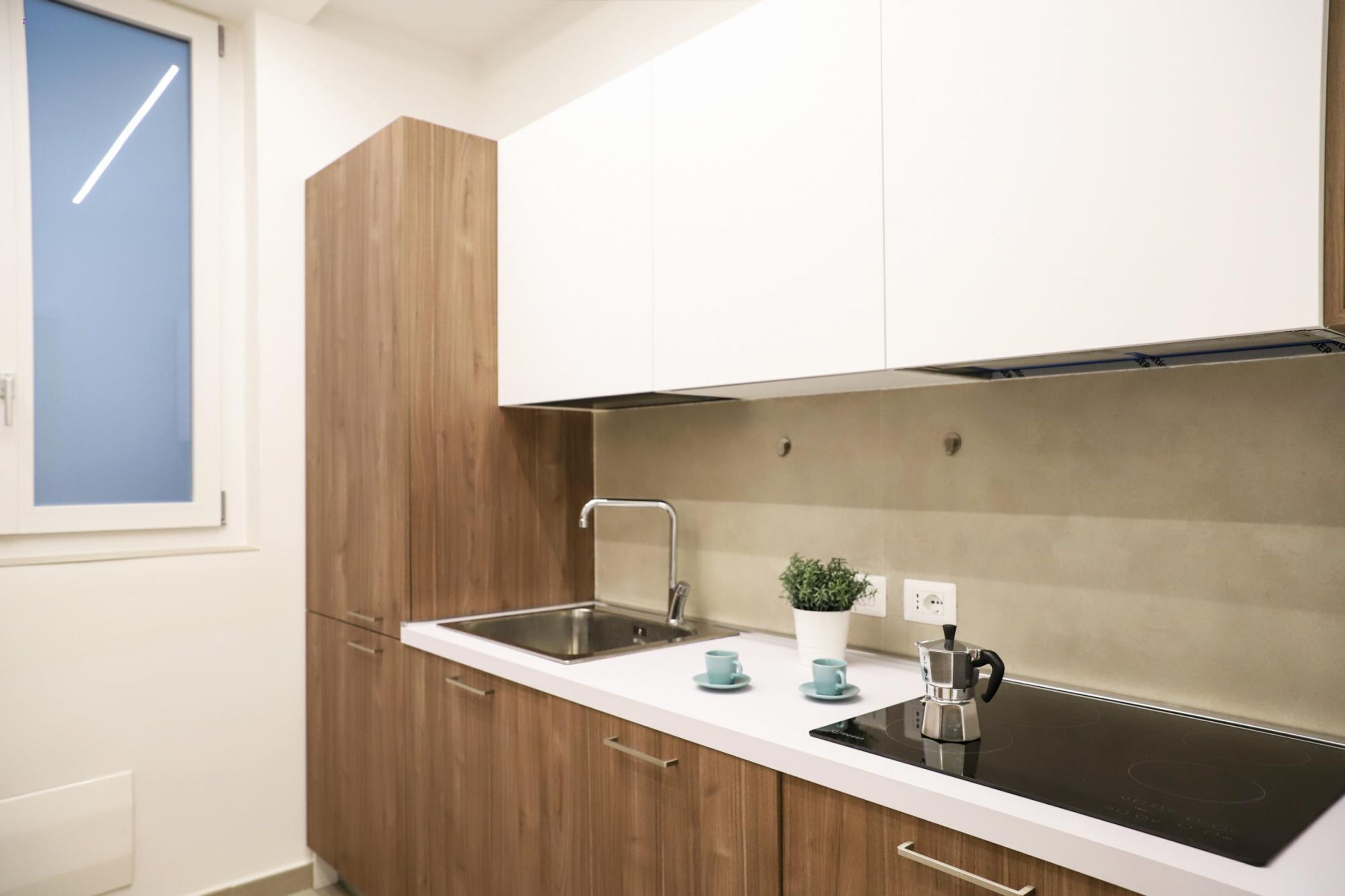 A modern kitchen with a white countertop, stainless steel sink, and a built-in stove.