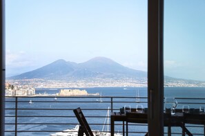 A view from a balcony overlooking a coastal city with a prominent mountain in the background.