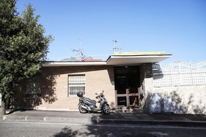 Een gebouw met een geparkeerde scooter, een hek en een stenen muur.