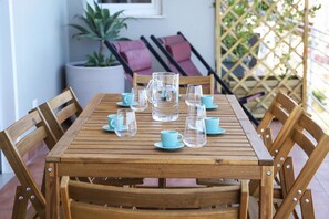 Een houten tafel met glazen en blauwe bekers, omringd door houten stoelen.