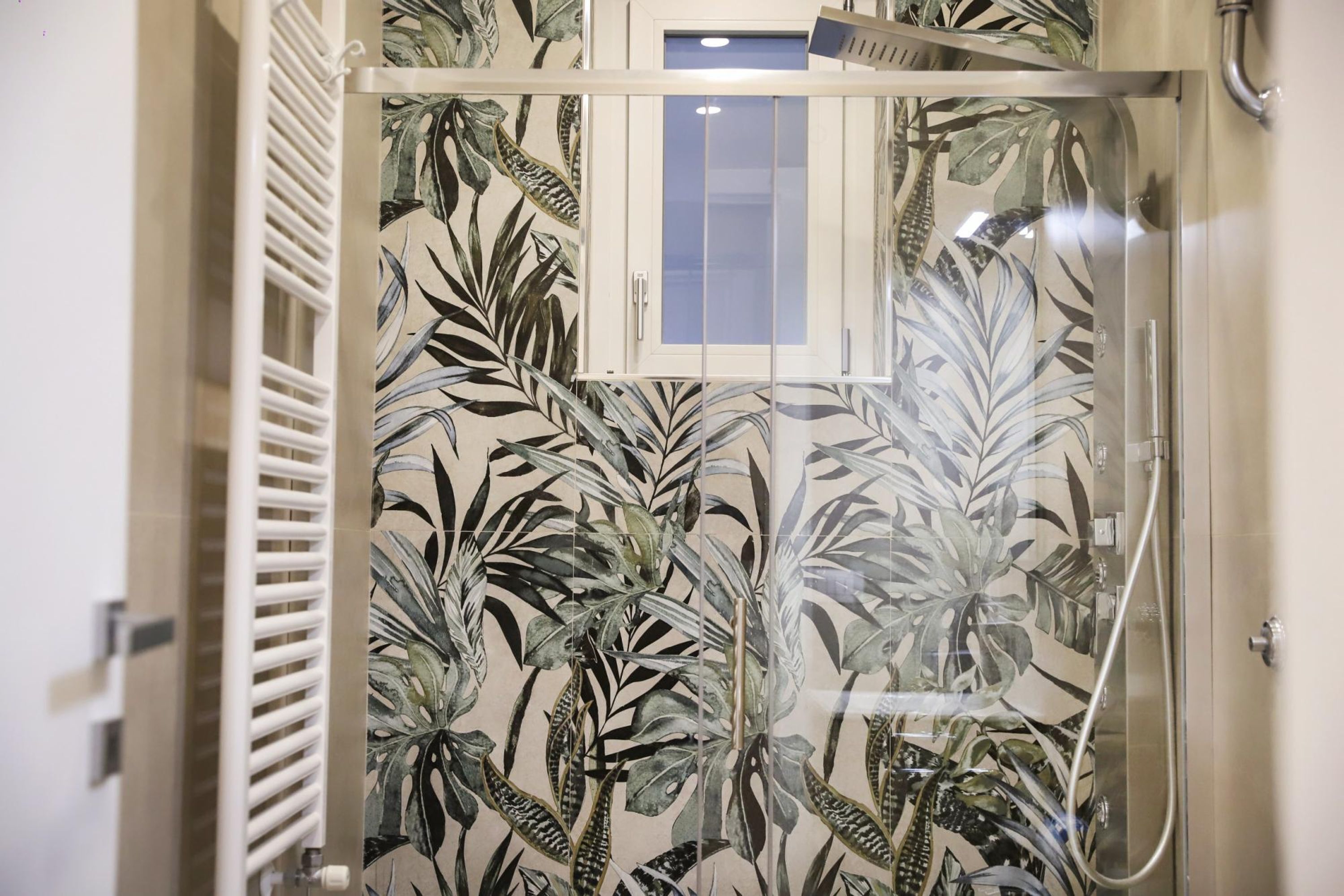 A shower enclosure with a glass door, a window, and a showerhead.