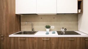 A kitchen with a sink, a coffee maker, and a potted plant on the countertop. - La Terrazza sul Golfo di Napoli by Wonderful Italy (Naples)