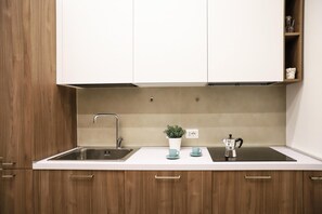 A kitchen with a sink, a coffee maker, and a potted plant on the countertop. - La Terrazza sul Golfo di Napoli by Wonderful Italy (Naples)
