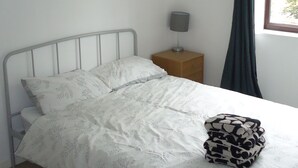 A single bed with a metal frame, a bedside table with a lamp, and a window with curtains. - 3 bed House Mkt Deeping - nr Peterborough Stamford (Peterborough)