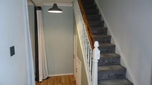 A staircase with a wooden handrail and white balusters, leading to a landing with a light fixture. - 3 bed House Mkt Deeping - nr Peterborough Stamford (Peterborough)