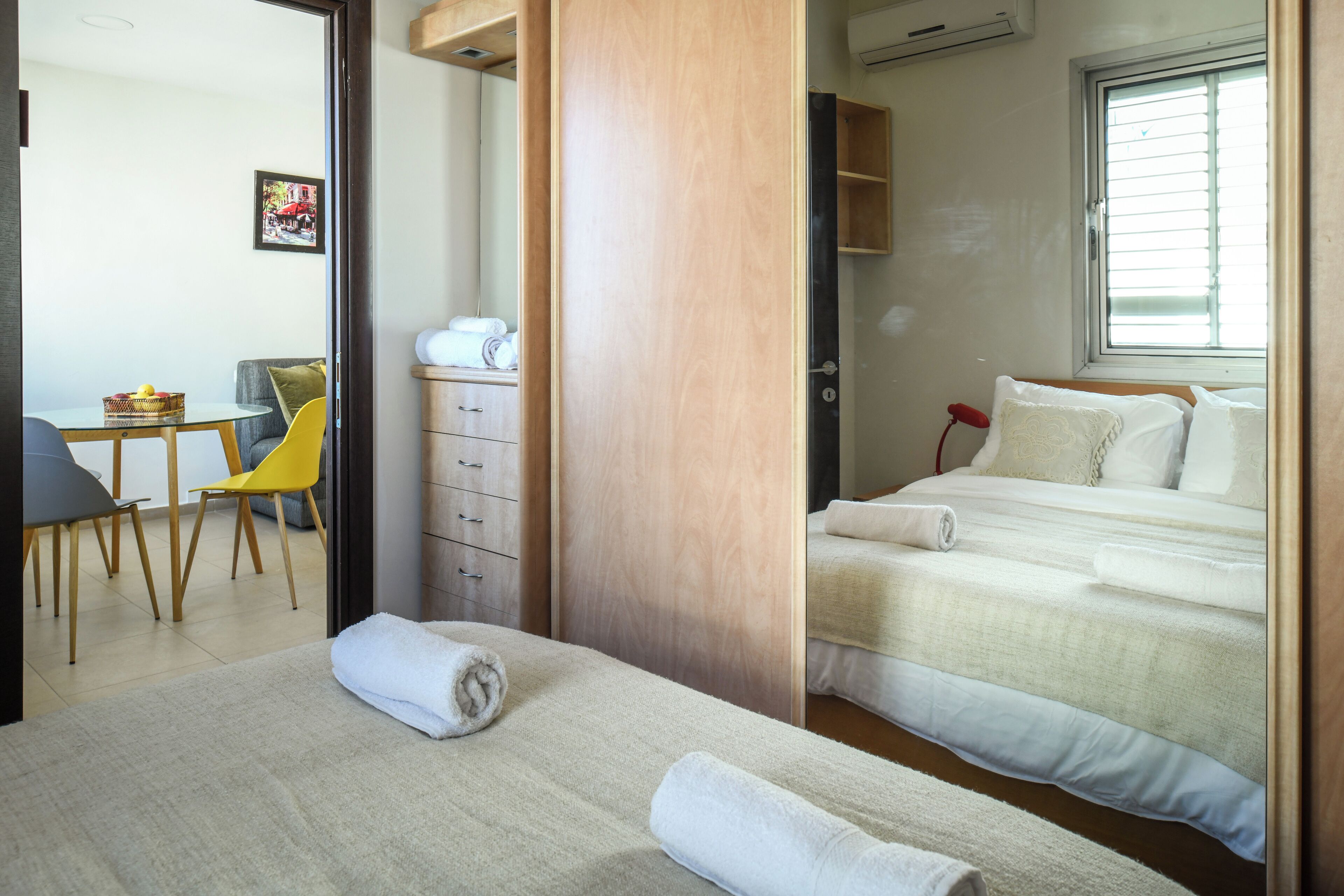 A hotel room with a bed, a desk with a chair, a small table, and a window.