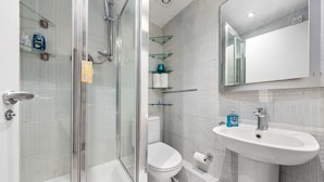 A modern bathroom with a glass shower enclosure, a white toilet, and a sink with a mirror above it. - Immaculate 1-bed Studio in London (London)