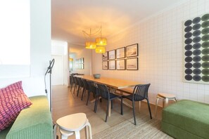Un espace repas moderne avec une table en bois et des chaises noires, un canapé vert et un petit tabouret.