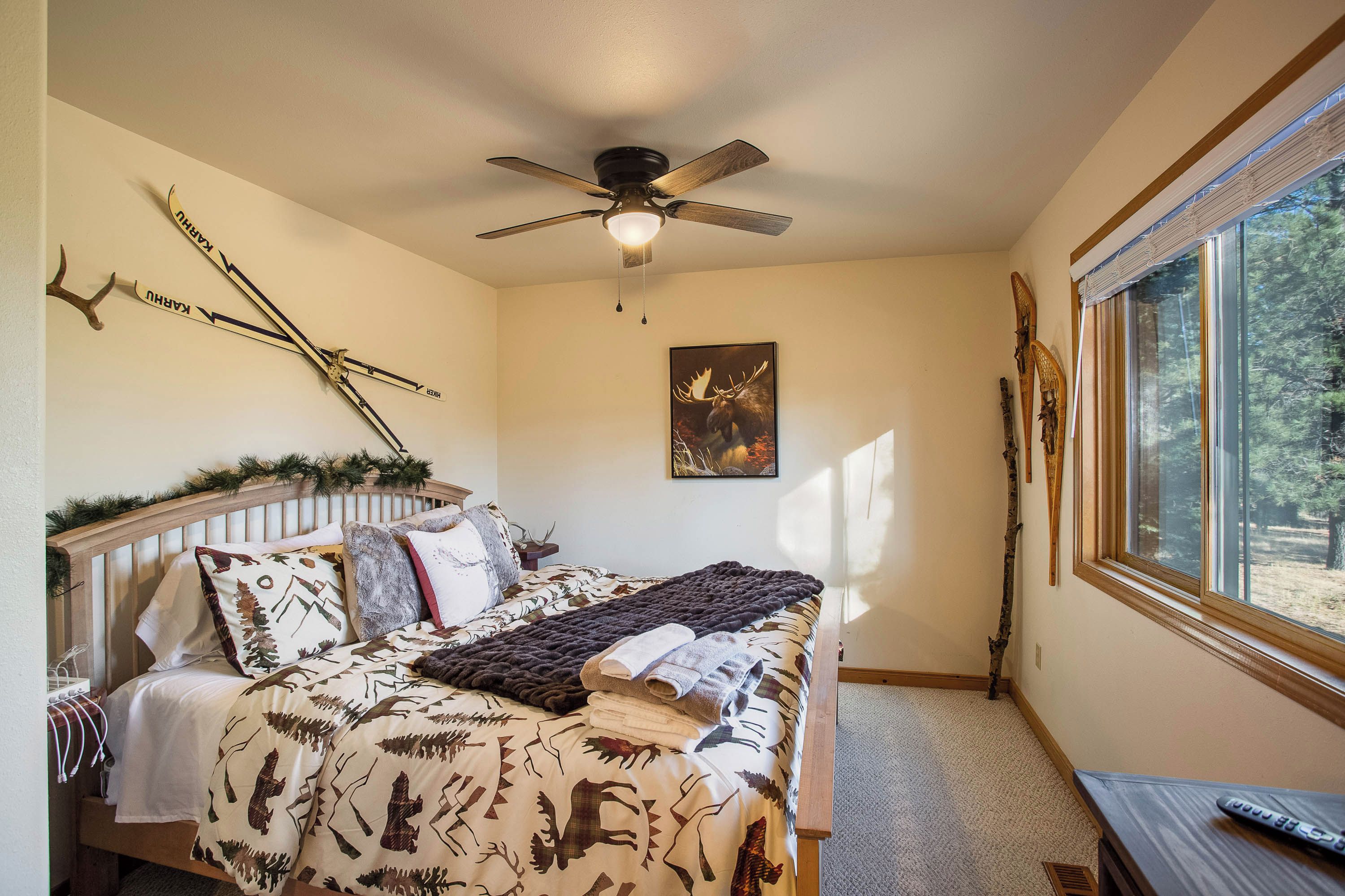 Une chambre à coucher avec un lit, un ventilateur de plafond, une fenêtre et des décorations murales.