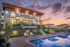 A modern villa with a pool, outdoor seating, and a landscaped garden.