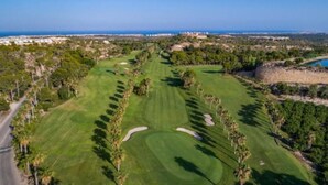 Un campo da golf con vista sull'oceano e una strada a sinistra.