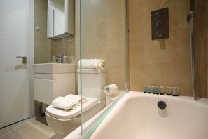 Ein modernes Badezimmer mit einer gläsernen Duschkabine, einer weißen Toilette und einer Badewanne.