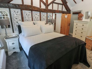 A bedroom with a bed, bedside tables, a dresser, and a fan.