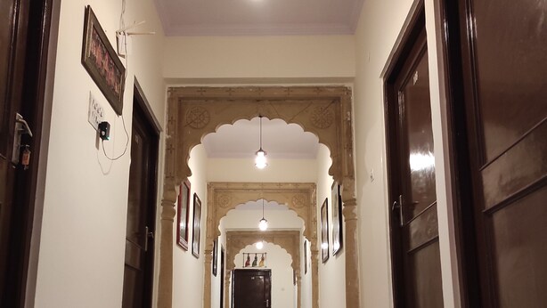 A corridor with marble flooring, a hanging light fixture, and a door with the number 107. - Hotel Sohandeep (Jaisalmer)