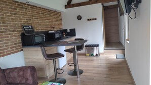 A modern kitchen with a brick wall, a dining area with bar stools, a sofa, and a coffee machine.