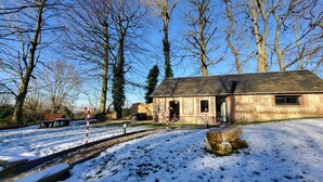 A brick building with a stone entrance, surrounded by snow-covered ground and leafless trees.