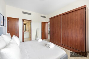 Une chambre d’hôtel avec un grand lit, une armoire en bois et une salle de bain visible à travers une porte ouverte.
