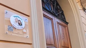 A wooden double door with a decorative top, a sign with a QR code, and a small window above the door. - Bologna Homestay (Bologna)