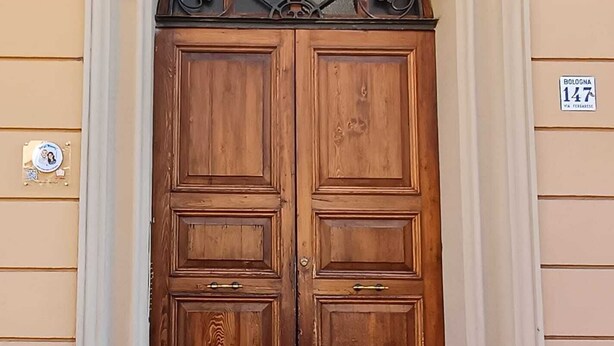 A double wooden door with a decorative metal arch above it. - Bologna Homestay (Bologna)