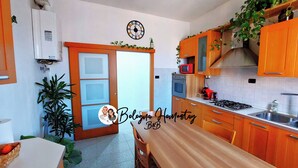 A kitchen with wooden cabinets, a microwave, a stove, and a sink. - Bologna Homestay (Bologna)
