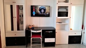 A room with a desk, chair, TV, and built-in shelving. - Bologna Homestay (Bologna)