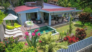 Ein modernes Haus mit Swimmingpool, Sitzgelegenheit im Freien und üppigem Garten.