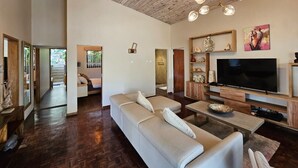 Ein modernes Wohnzimmer mit einer großen Eckcouch, einem Flachbildfernseher und einer Holzbalkendecke.
