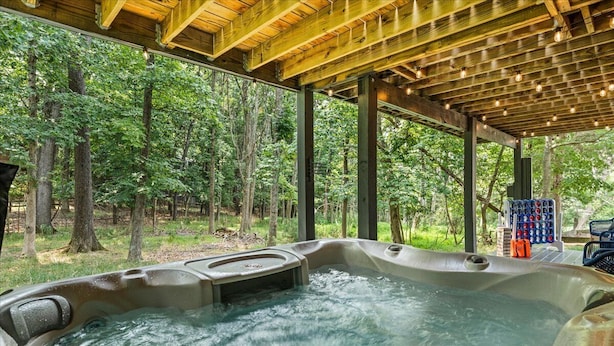 Un jacuzzi en un área boscosa con una pérgola de madera encima.