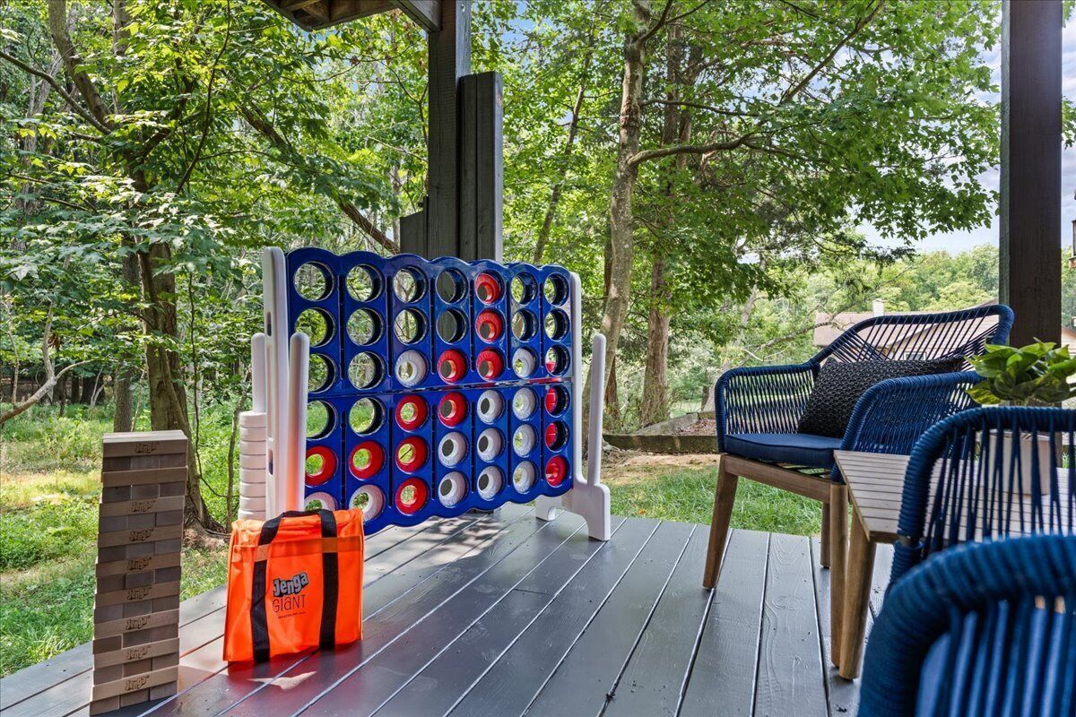 A wooden deck with a Jenga game set up, a Jenga bag, and a blue chair.