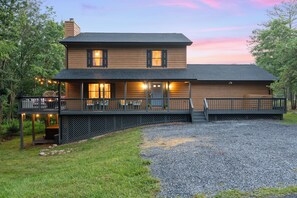 A two-story wooden house with a porch and outdoor seating area.