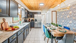 Una cocina moderna con armarios oscuros, techo de madera y un comedor con pared estampada.