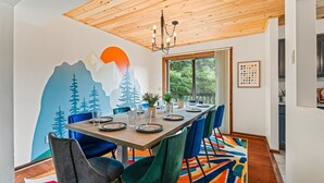 Un comedor con techo de madera, un mural de montañas y una alfombra colorida.