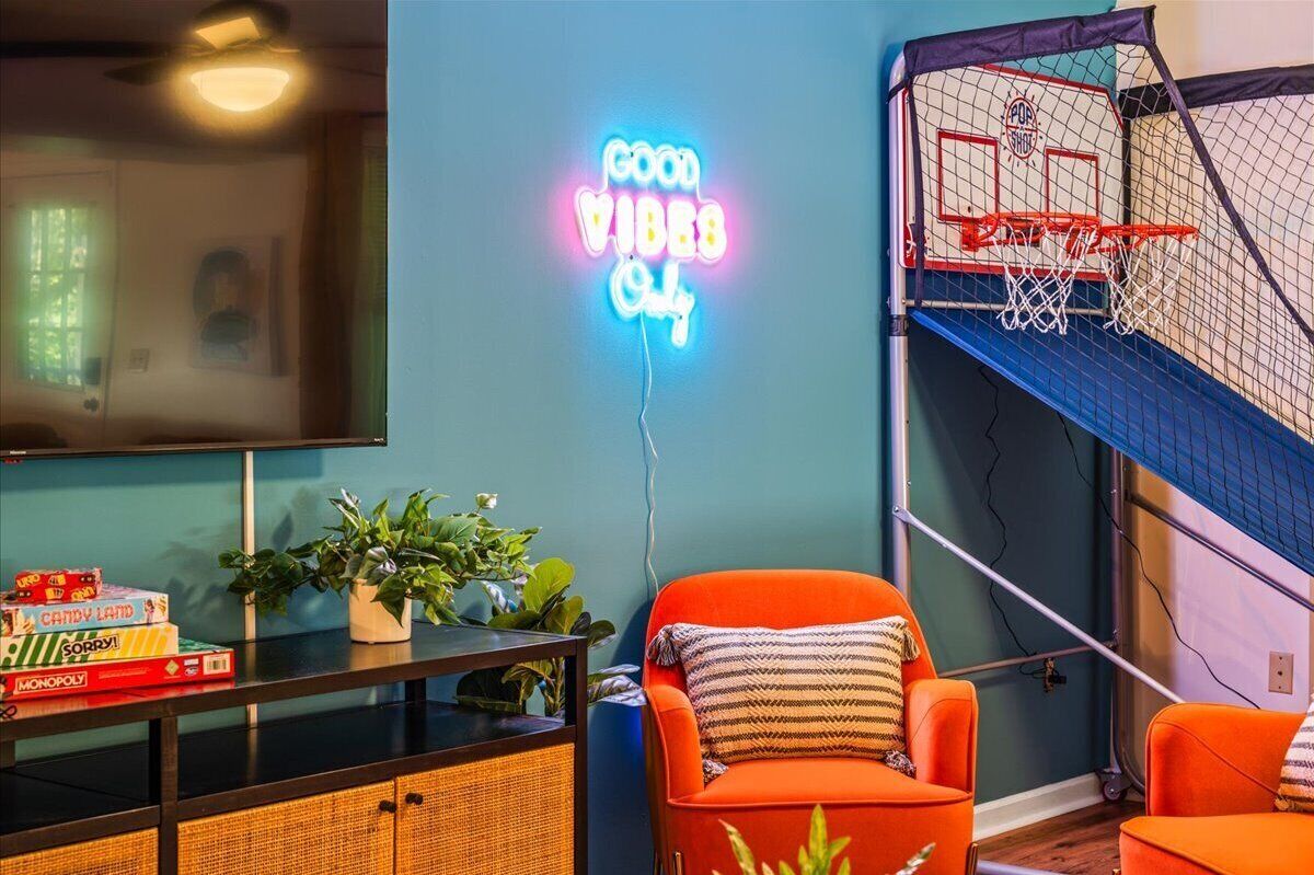 Una habitación con un letrero de neón, un aro de baloncesto y un sofá.