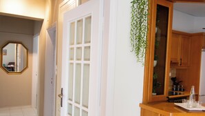 A hallway with a white door, a mirror, and a wooden cabinet with a sink and glasses. - Renaissance City Apartment  (Heraklion)