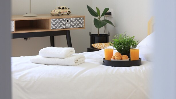 A neatly arranged bedroom with a bed, a desk with a lamp, a small toy car, and framed artwork on the wall. - Renaissance City Apartment  (Heraklion)