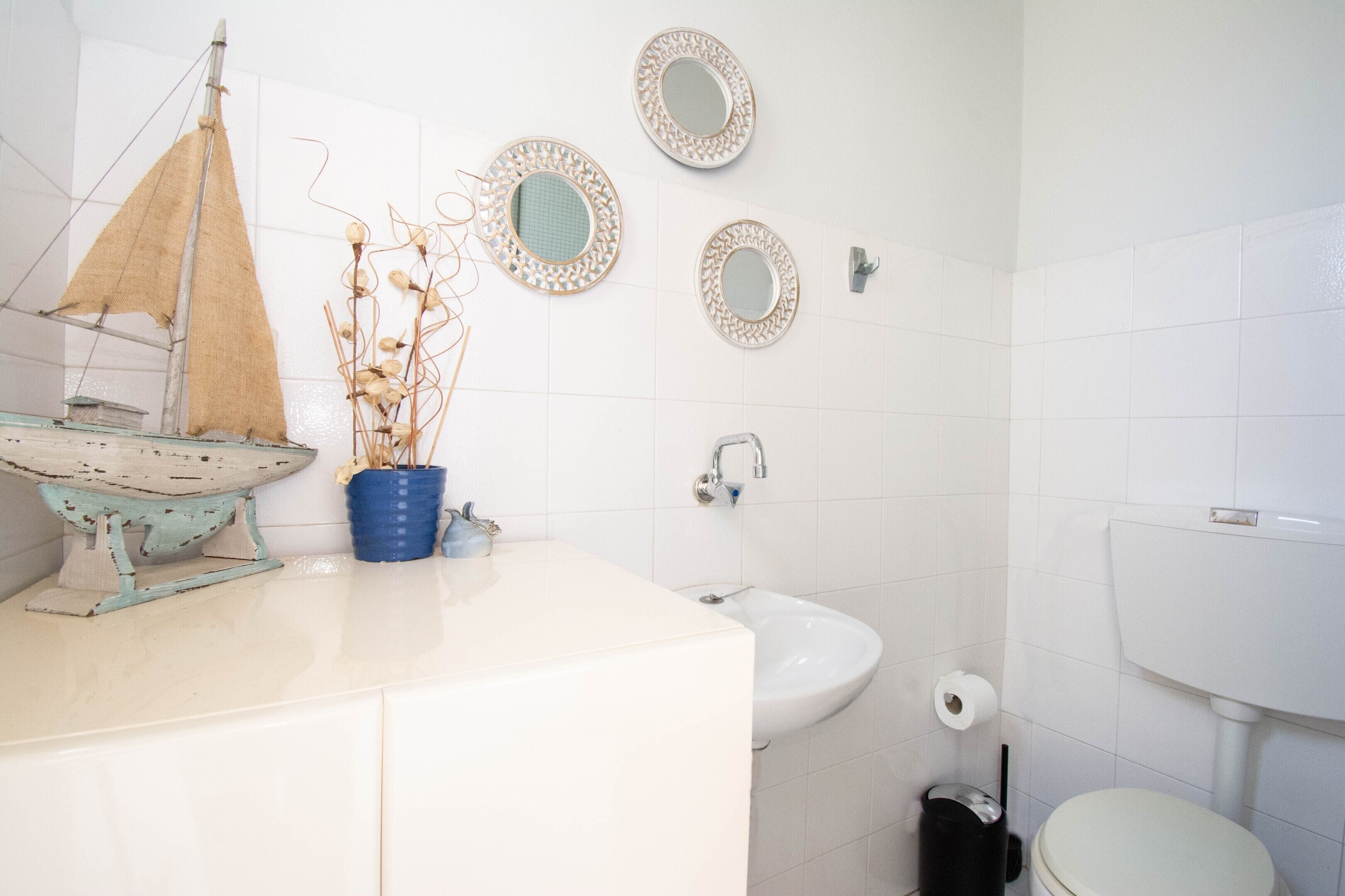 Baño con lavamanos, inodoro y espejos decorativos.