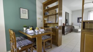 A dining area with a wooden table and chairs, a bookshelf, and a kitchen area in the background. - Renaissance City Apartment  (Heraklion)